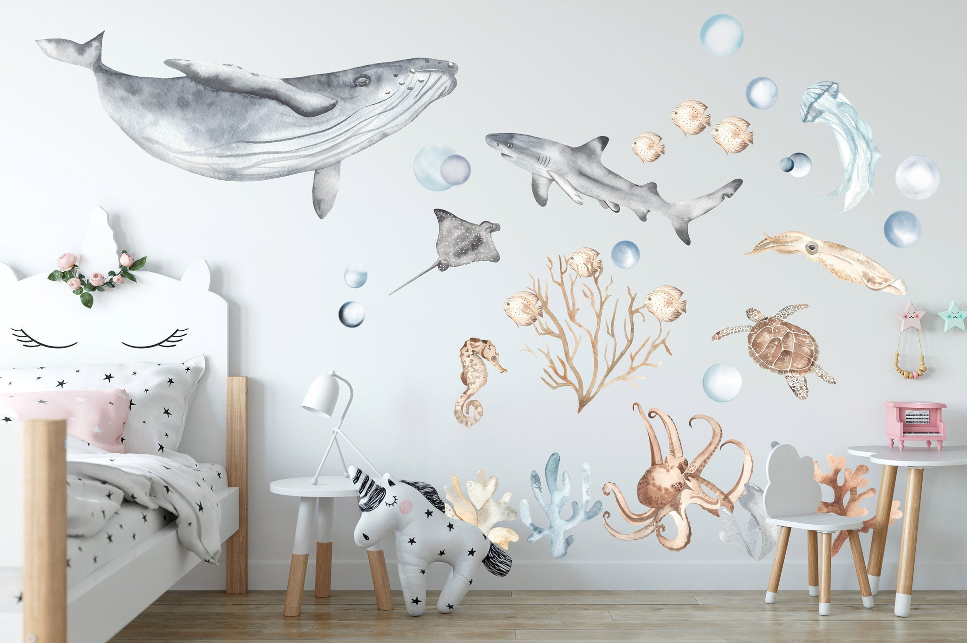 Children‘s bedroom featuring sea life wall decals with watercolor marine animals, including whales, sharks, turtles, octopus, and coral, adding a playful ocean theme to the decor.