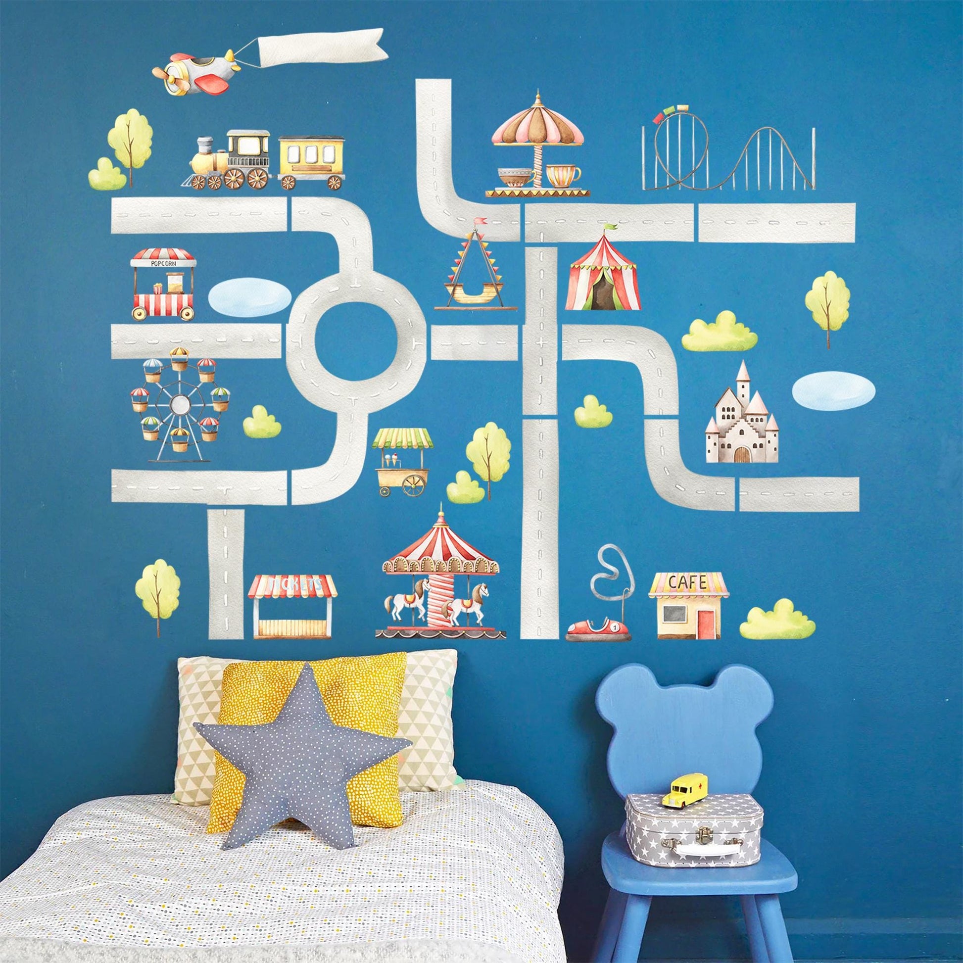Children&#39;s bedroom showcasing amusement park fabric wall decals, including roller coaster, ferris wheel, and carnival stalls, set against a vibrant blue wall.